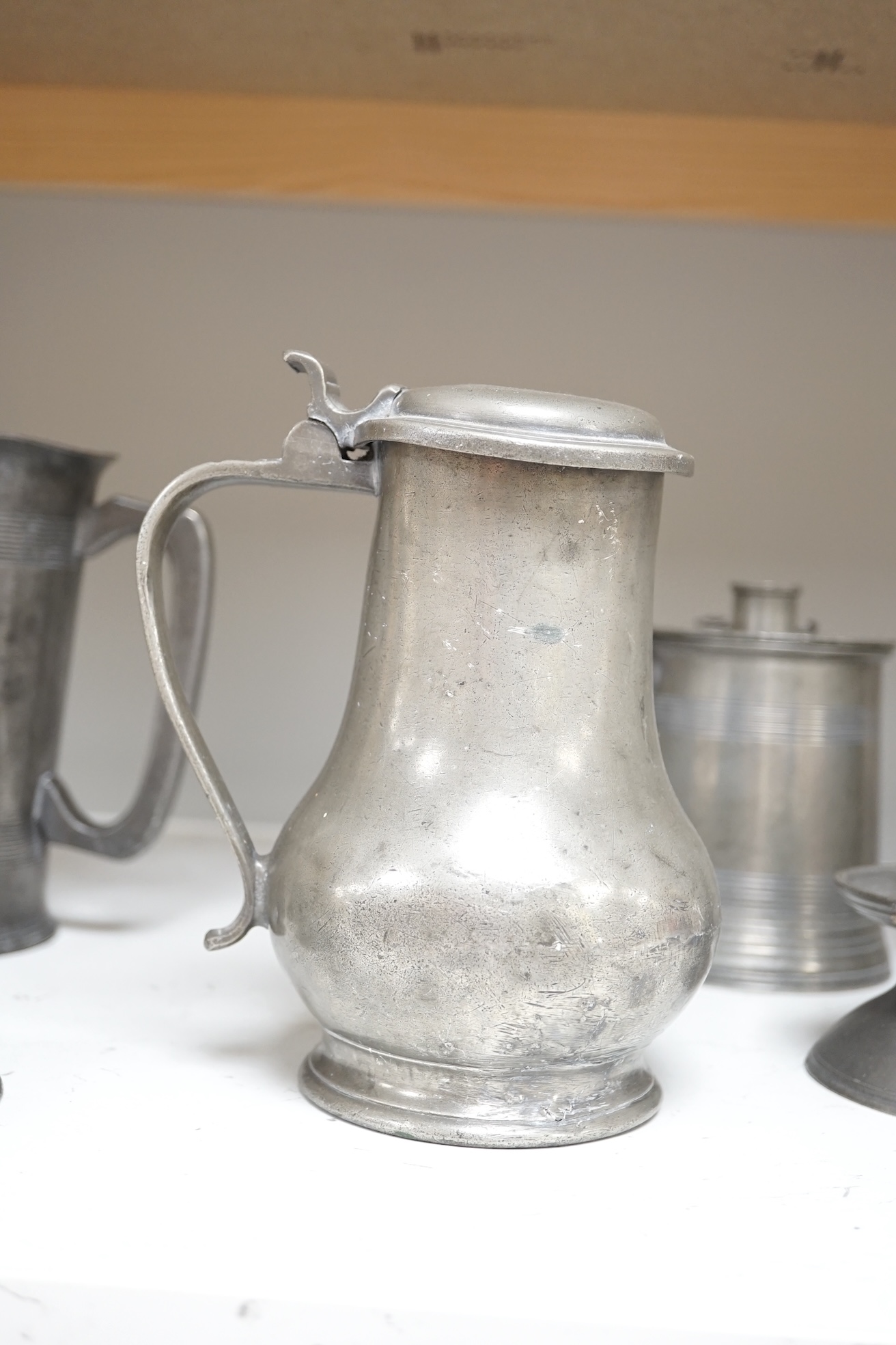 Six items of 18th century and later pewter including a jug, candlesticks, a pint measure, and a bronze hand bell, 24cm high. Condition - fair.